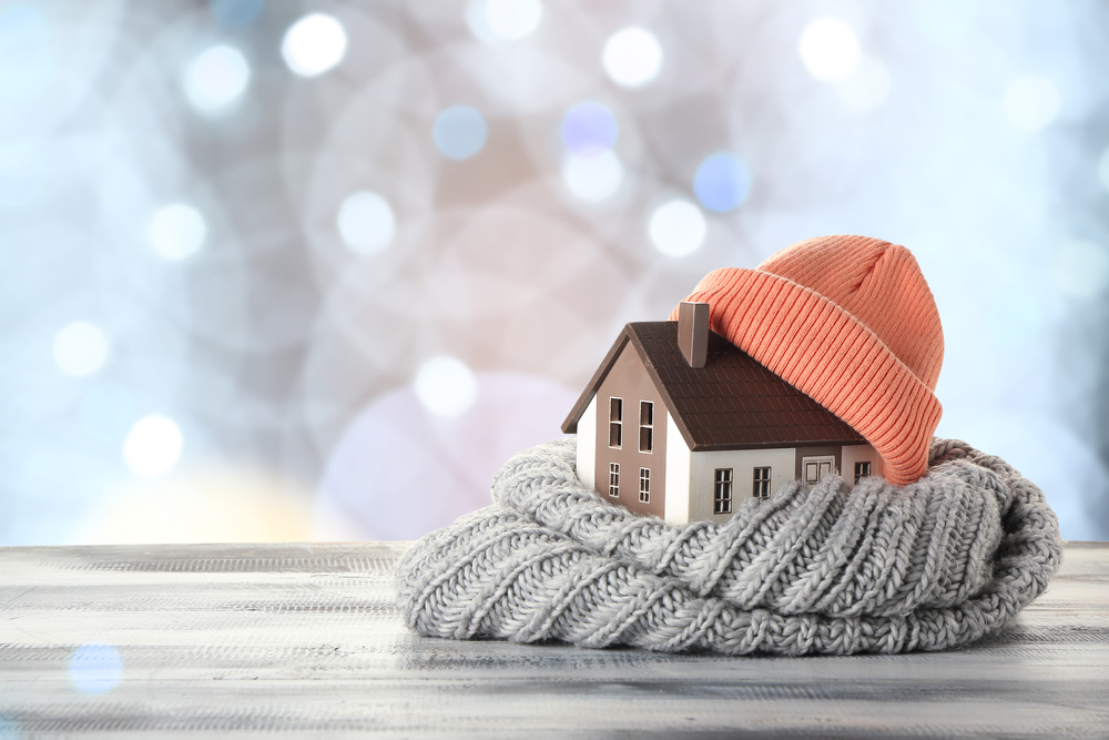 Figure,of,house,and,warm,clothes,on,table,against,blurred